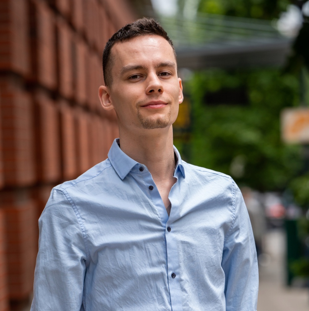 Image of Nathaniel smiling in front of a brick wall